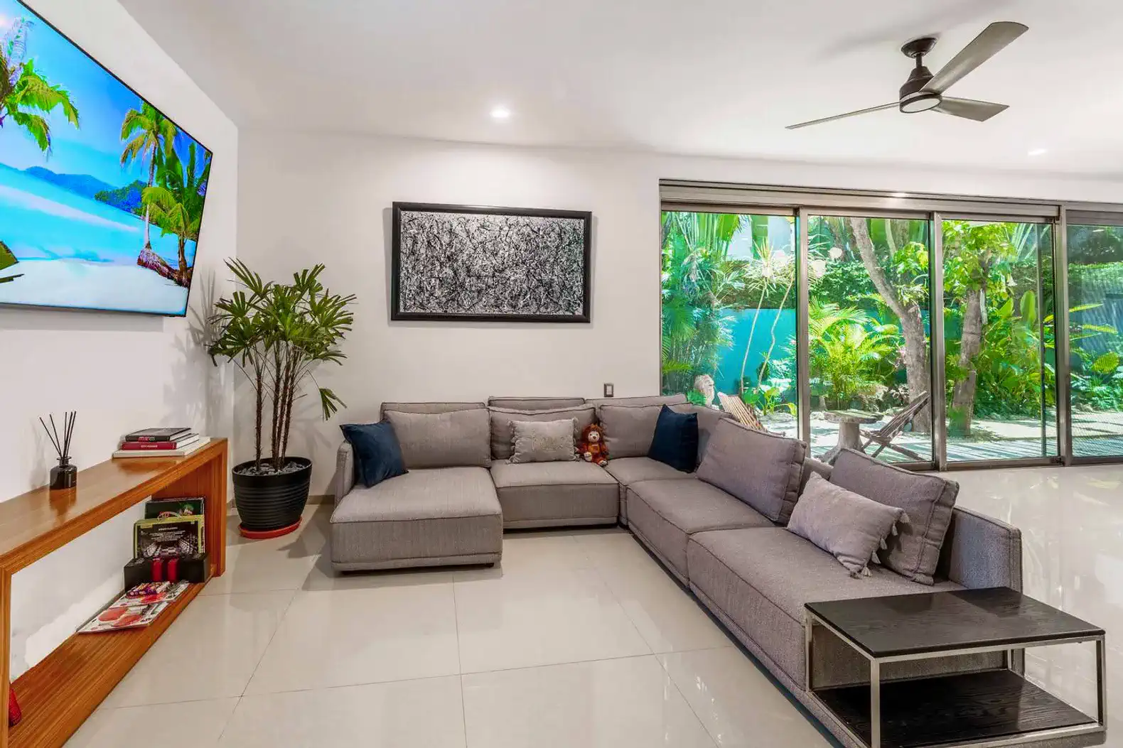 Sala moderna con sofá amplio, decoración elegante y vista al jardín tropical