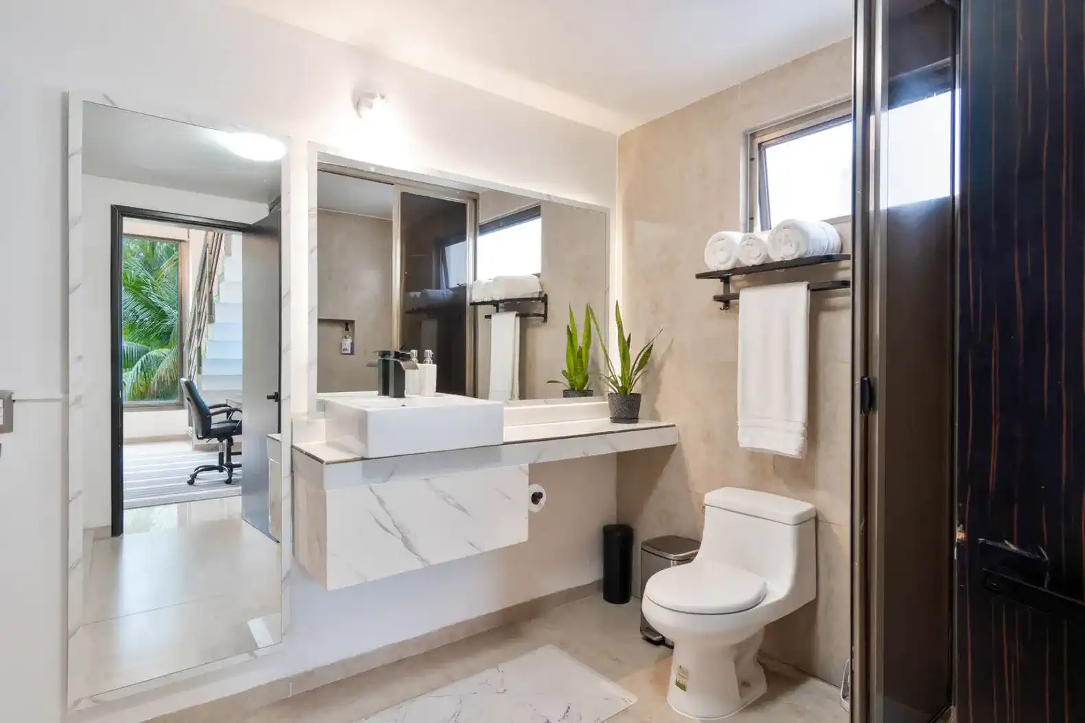 Baño moderno con lavabo de mármol, espejo grande y decoración minimalista