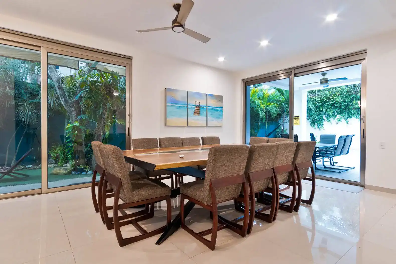 Amplio comedor con mesa para diez personas y vistas a un jardín tropical