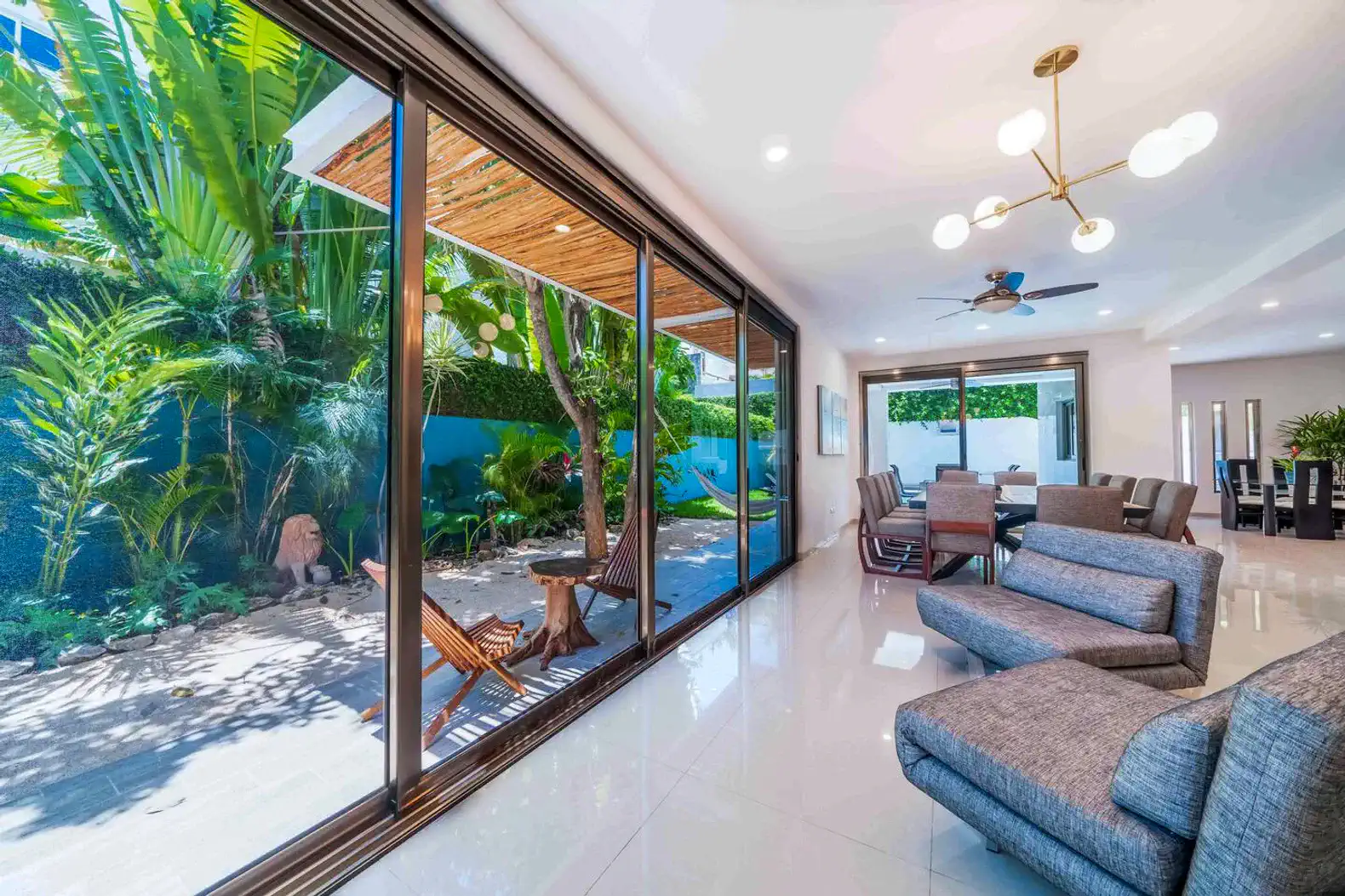 Sala moderna con grandes ventanales y vista al jardín tropical