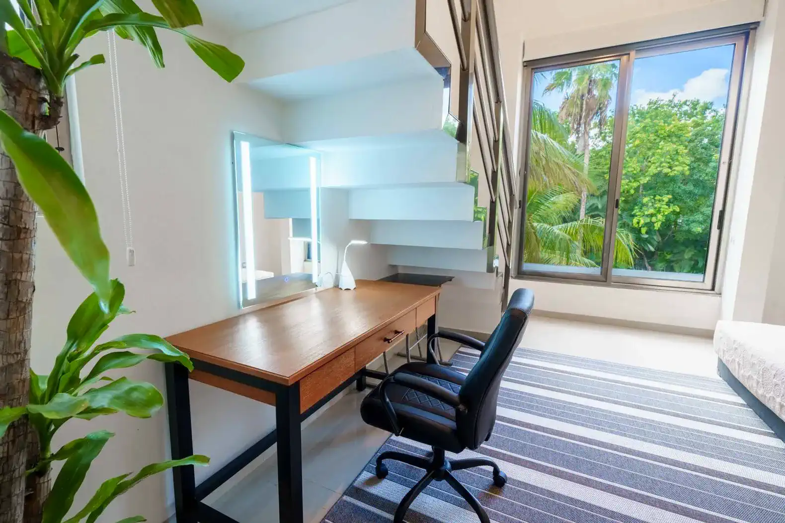 Escritorio moderno con silla en un espacio luminoso junto a una ventana con vista a la vegetación