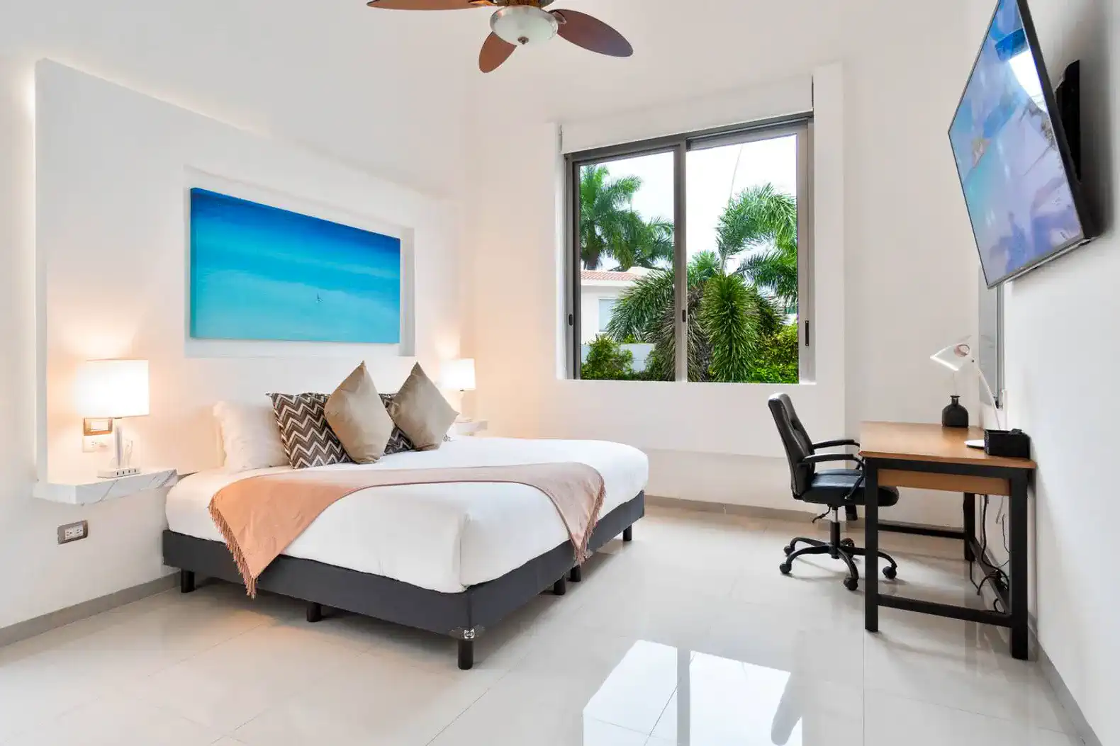 Habitación luminosa con cama grande, escritorio y ventana con vista a la vegetación