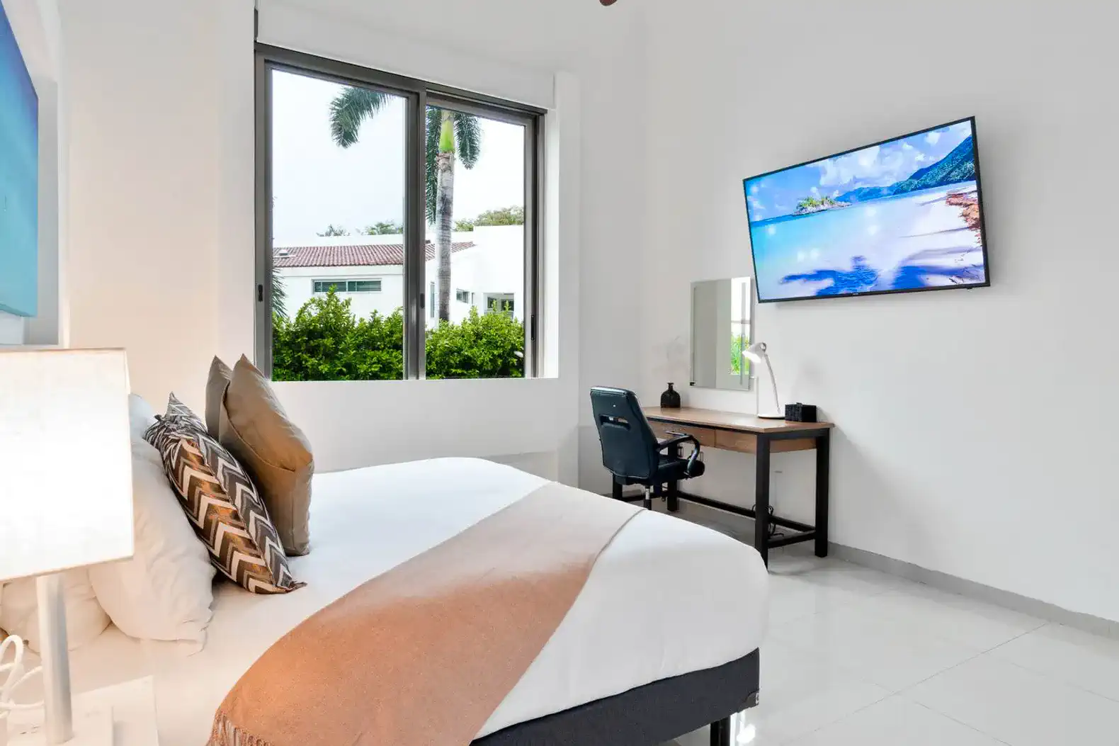 Habitación luminosa con cama cómoda, escritorio y ventana con vista al jardín