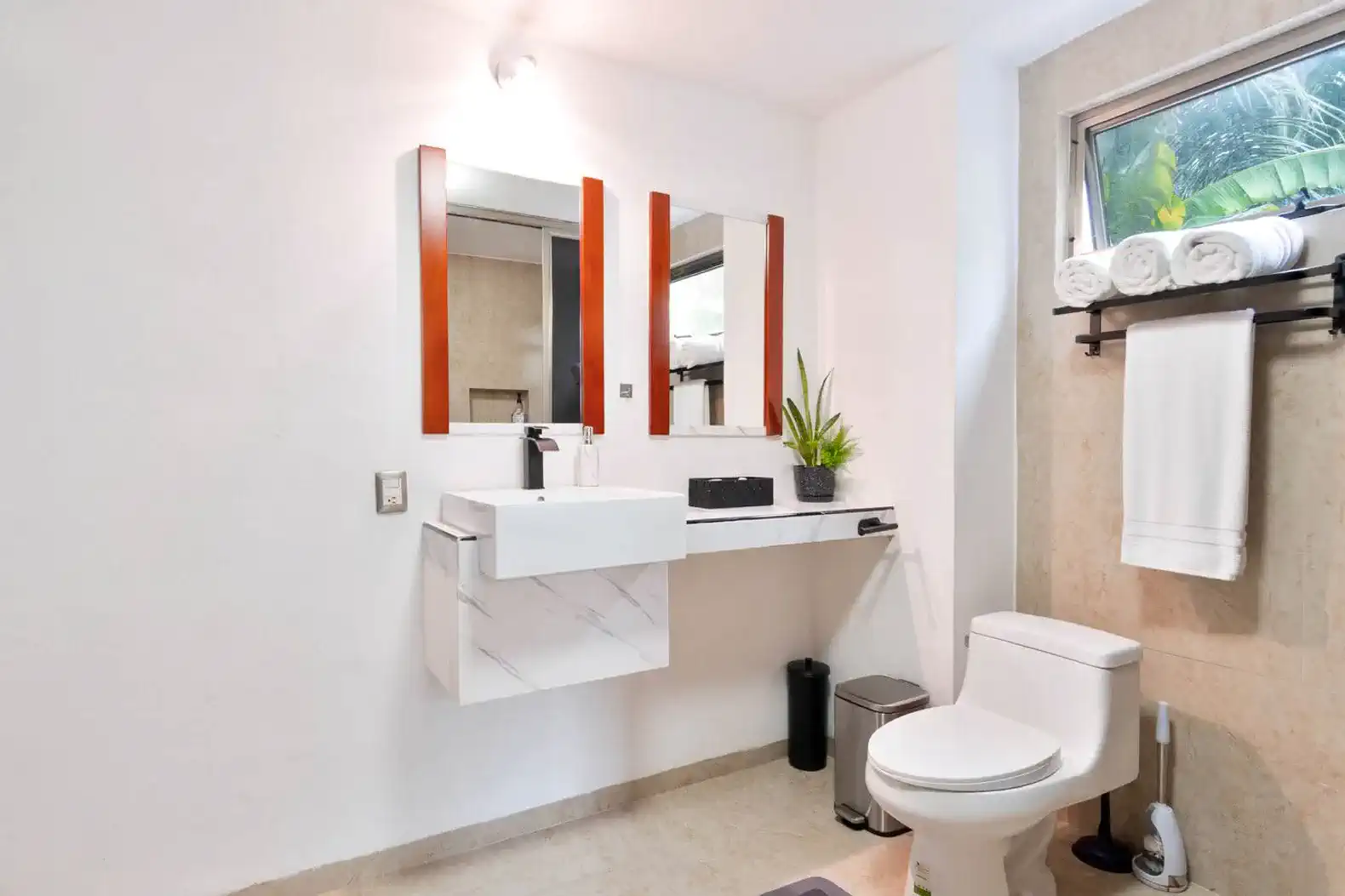 Baño moderno con lavabo flotante, espejo doble y decoración minimalista