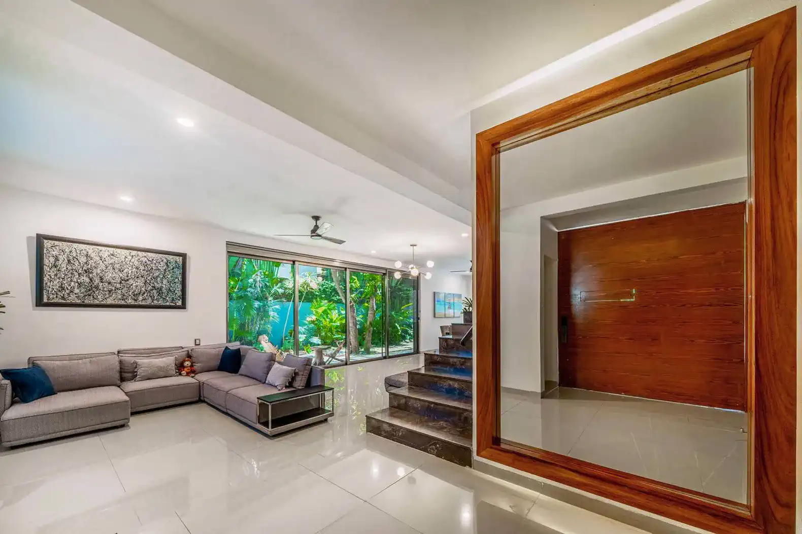Spacious living room with modern furniture and large windows overlooking greenery