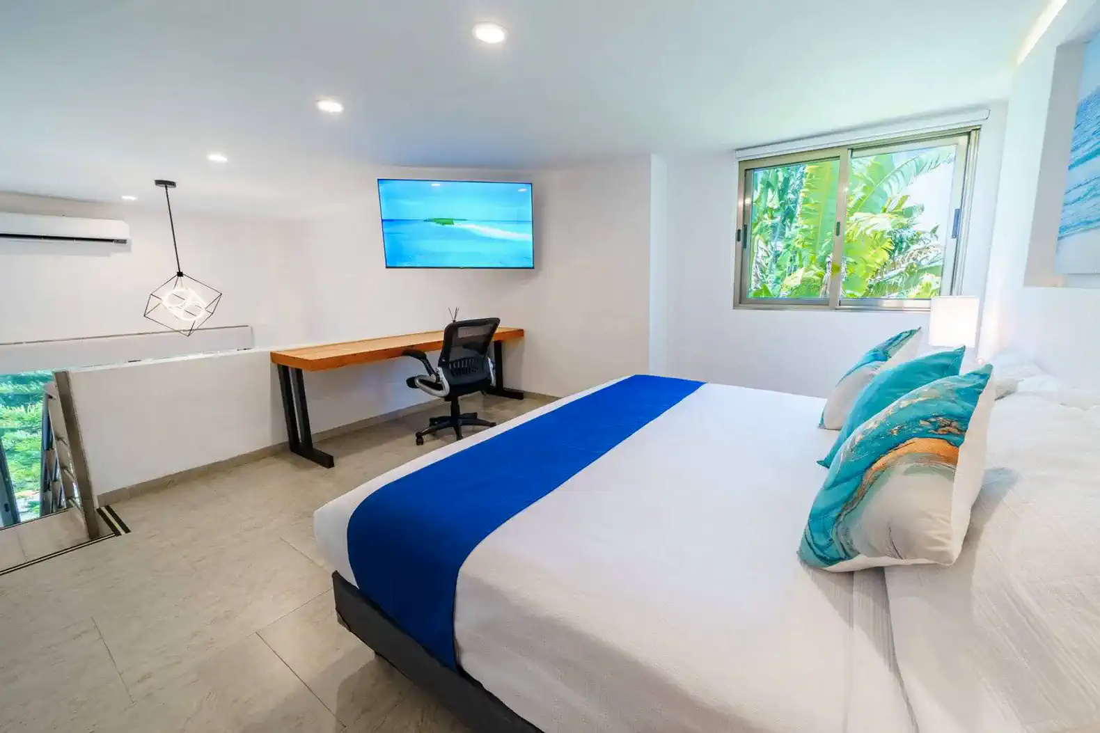 Habitación principal con cama grande, escritorio y ventana con vista a la vegetación