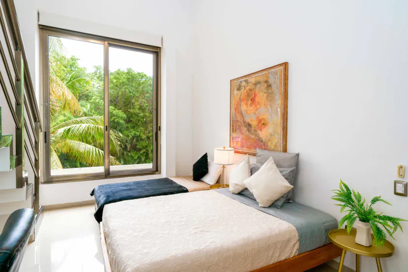 Bright modern bedroom with large window and lush tropical views