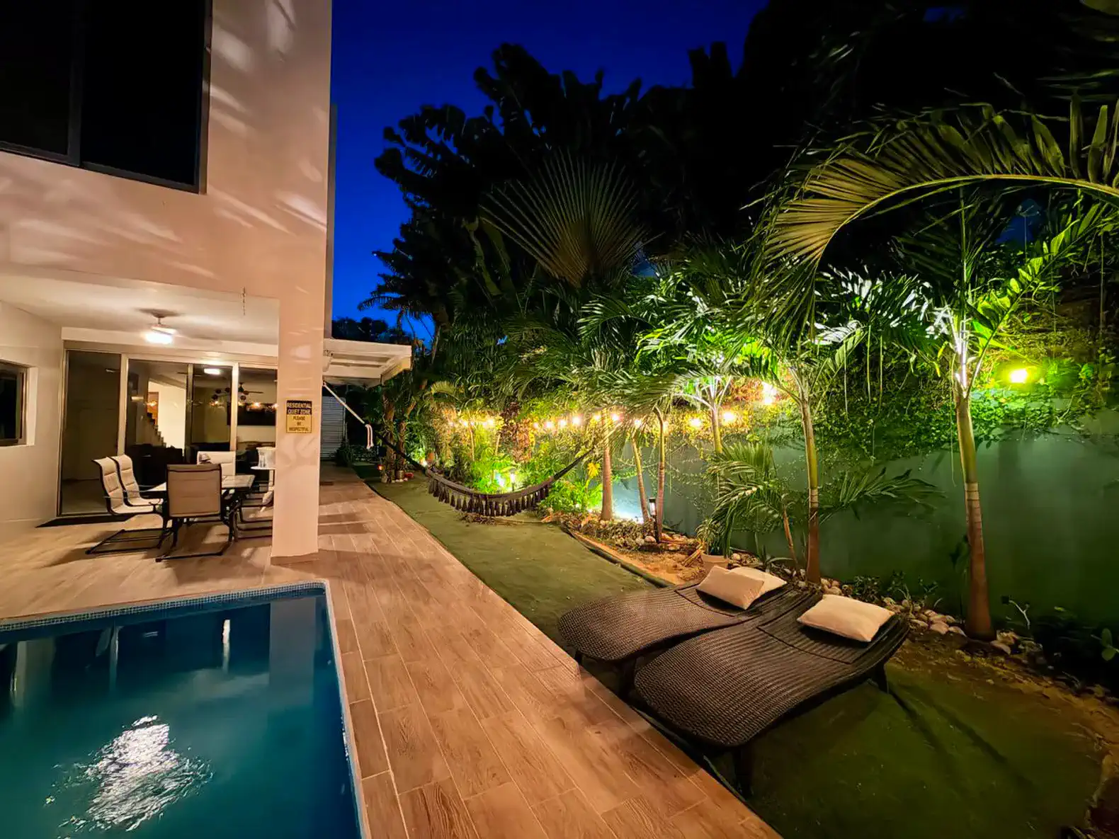 Zona exterior con piscina, tumbonas y jardín iluminado