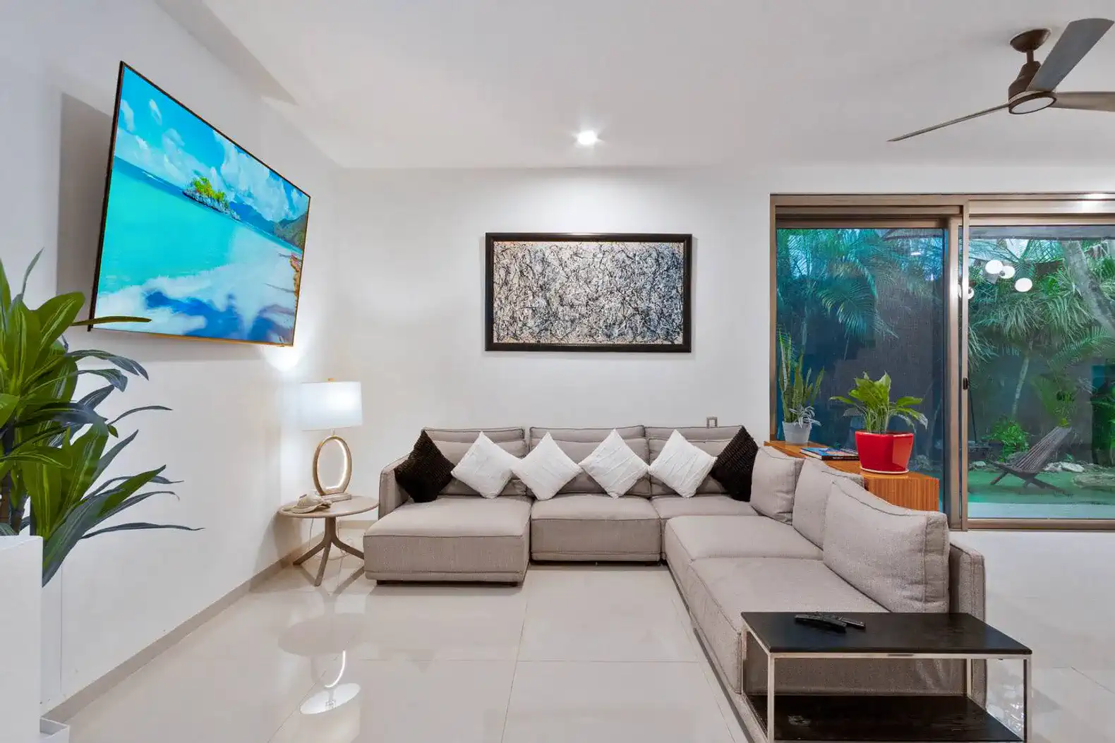 Sala moderna con sofá grande, televisor de pantalla plana y vista al jardín
