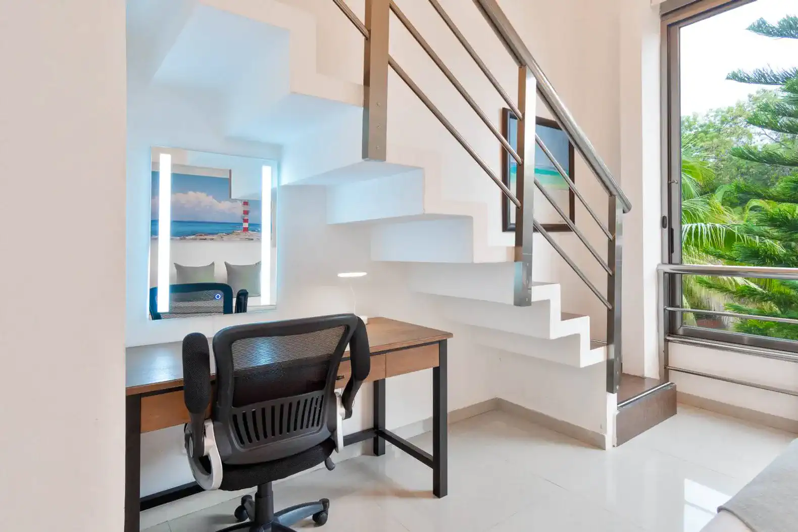 Escritorio moderno junto a una escalera con luz natural y vista a la vegetación exterior