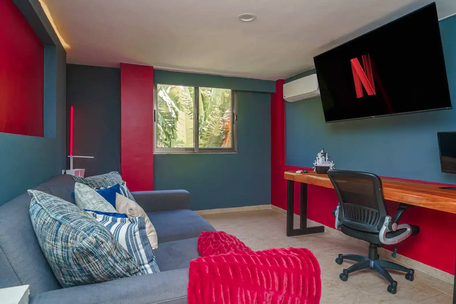 Sala de estar moderna con sofá, escritorio y pantalla de televisión