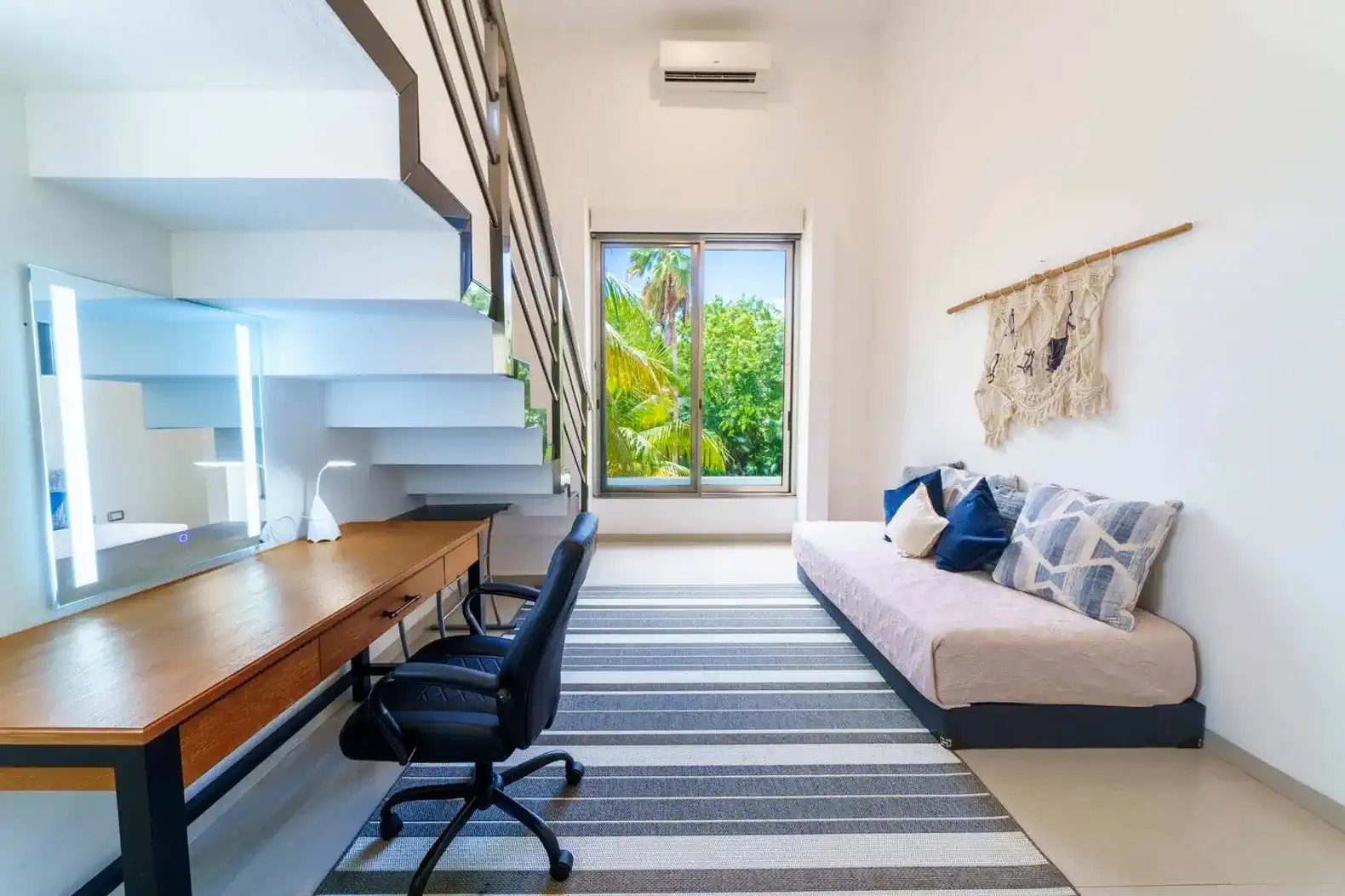 Habitación luminosa con escritorio, silla y ventana que ofrece vistas al exterior