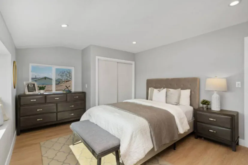Cozy master bedroom with a queen bed, dresser, and natural light from a window