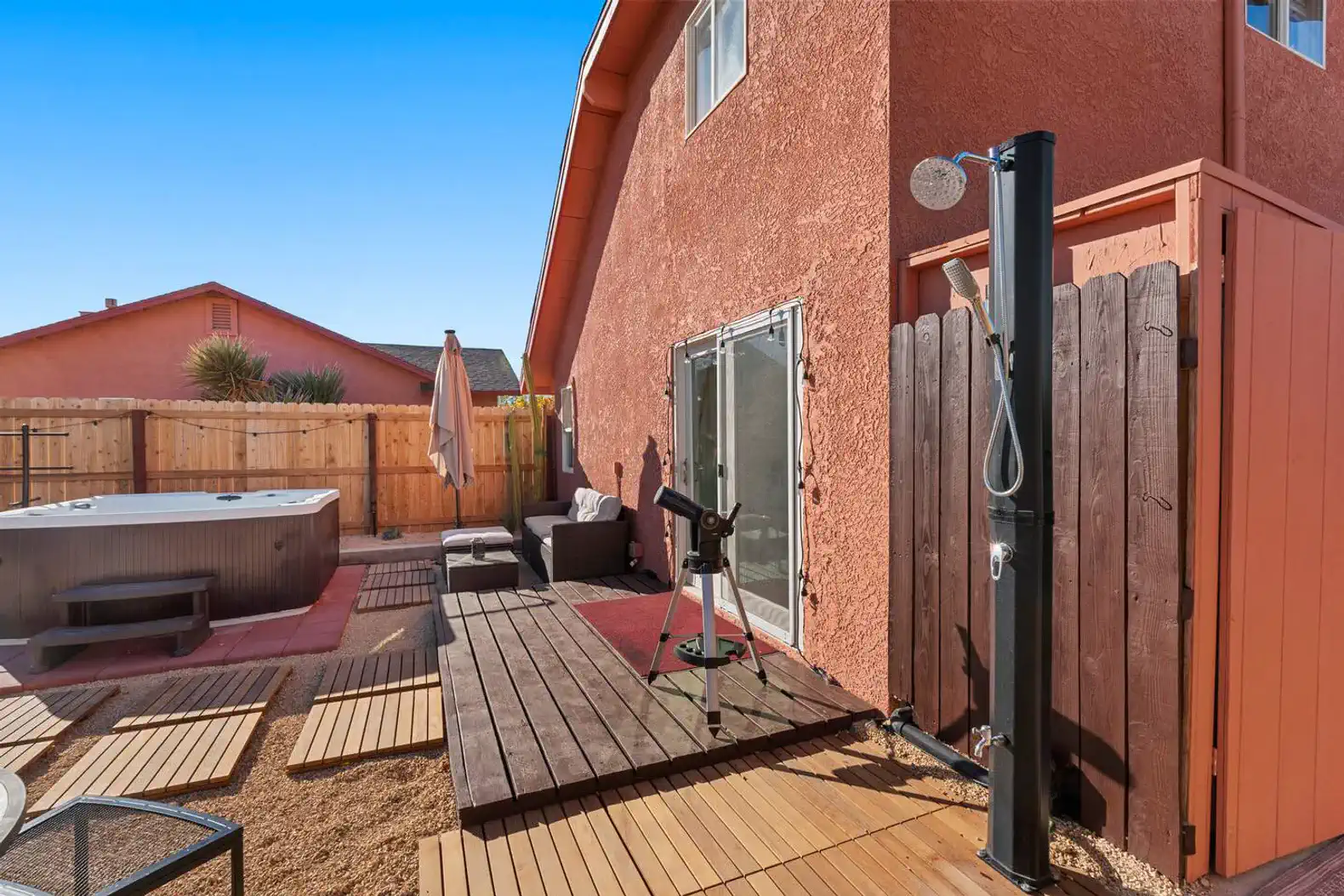 Outdoor area featuring a hot tub, shower, and seating on a wooden deck