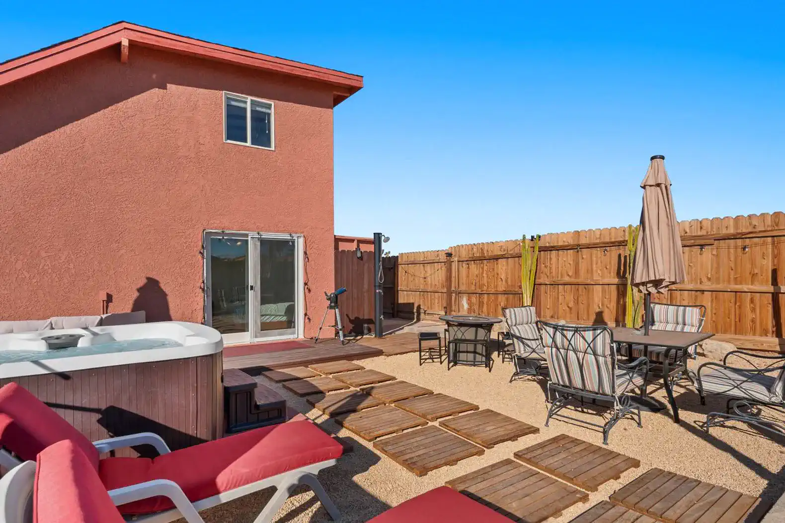 Outdoor patio area with seating, hot tub, and fenced yard