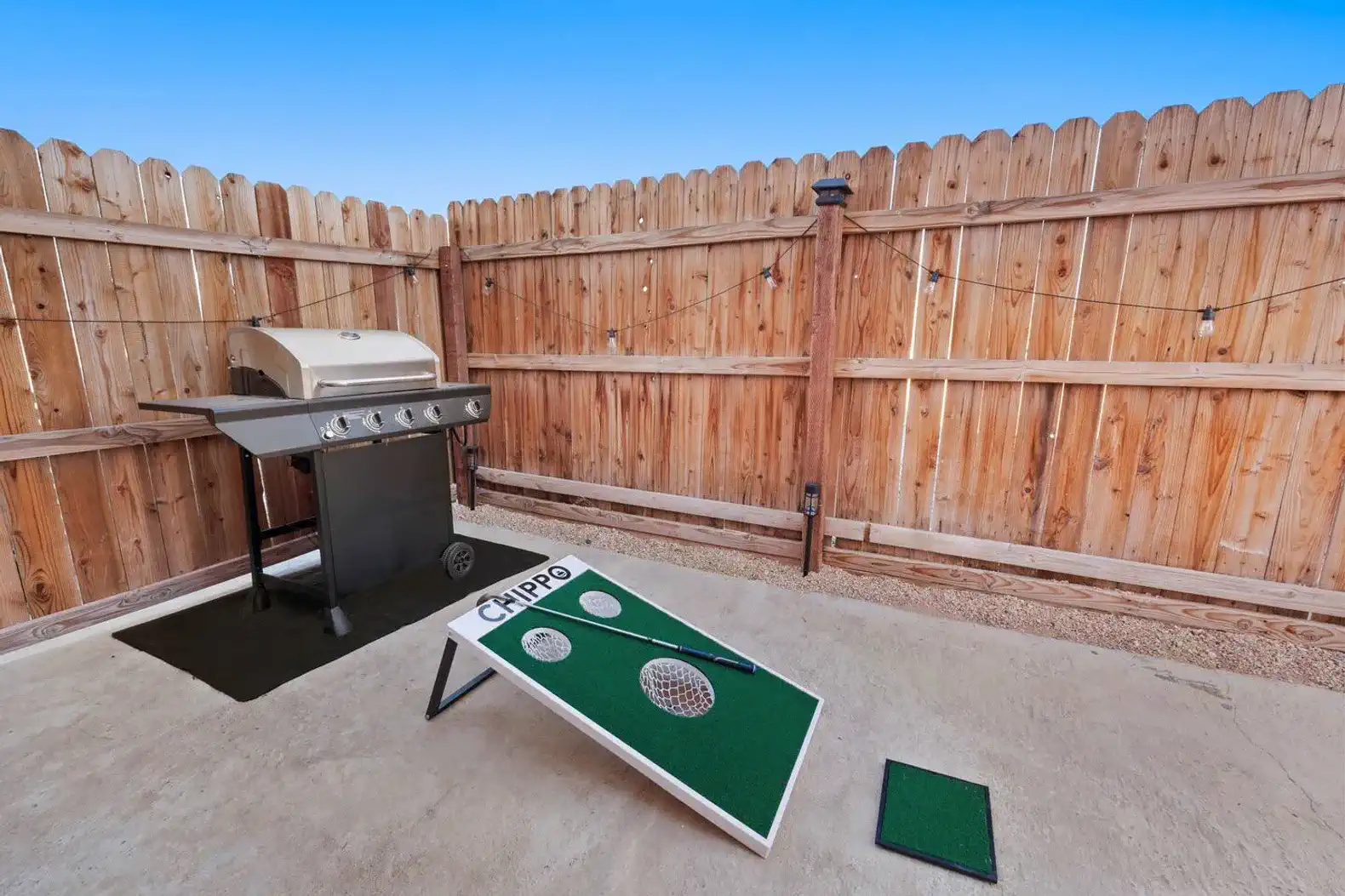 Outdoor grilling area with a barbecue grill and cornhole game
