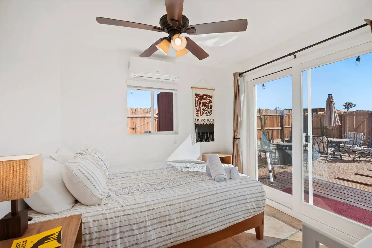 Cozy bedroom with a queen bed, ceiling fan, and sliding glass doors to an outdoor patio