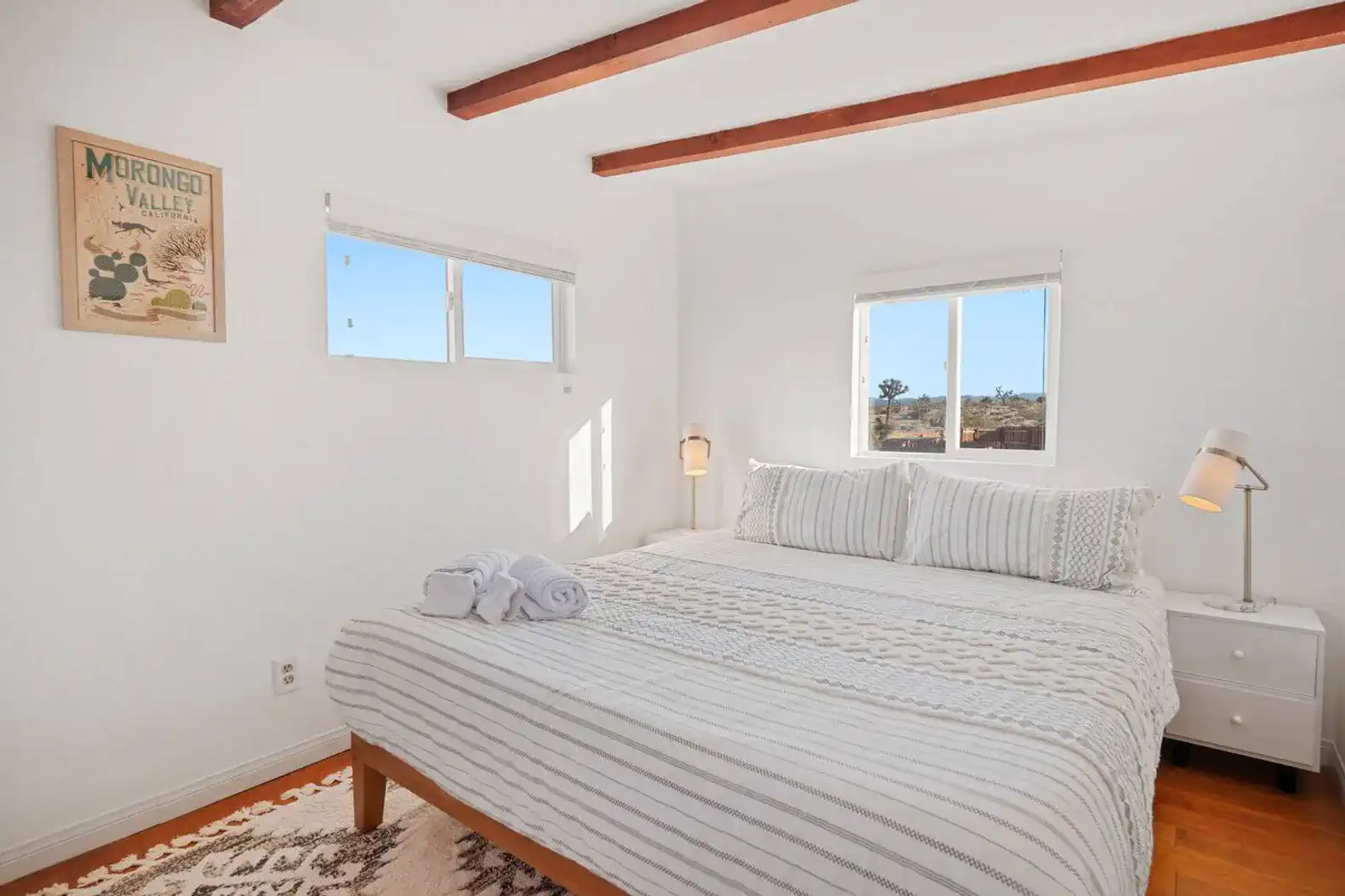 Cozy bedroom with a queen bed, natural light, and wooden beams