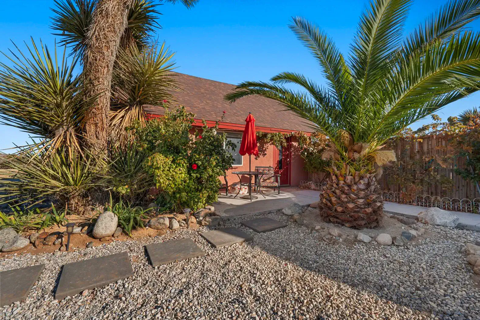 Charming outdoor area with palm trees and a red umbrella table