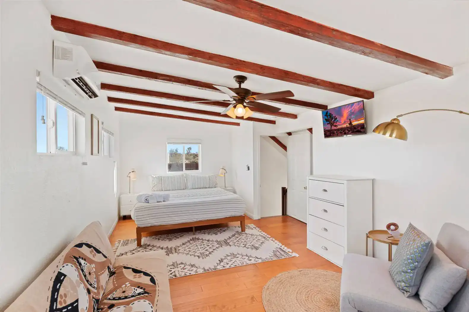 Cozy master bedroom with wooden beams, a comfortable bed, and seating area