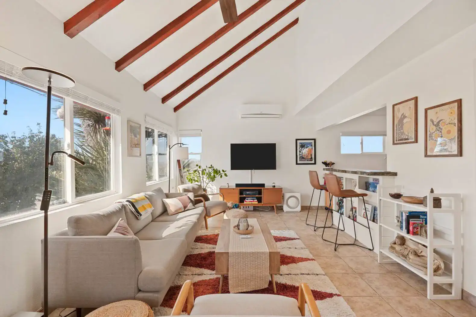 Bright living room with vaulted ceiling, comfortable seating, and large windows