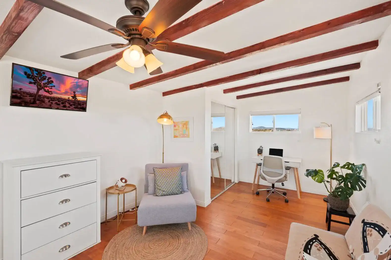 Cozy room with a chair, desk, and modern decor featuring wooden beams and a TV