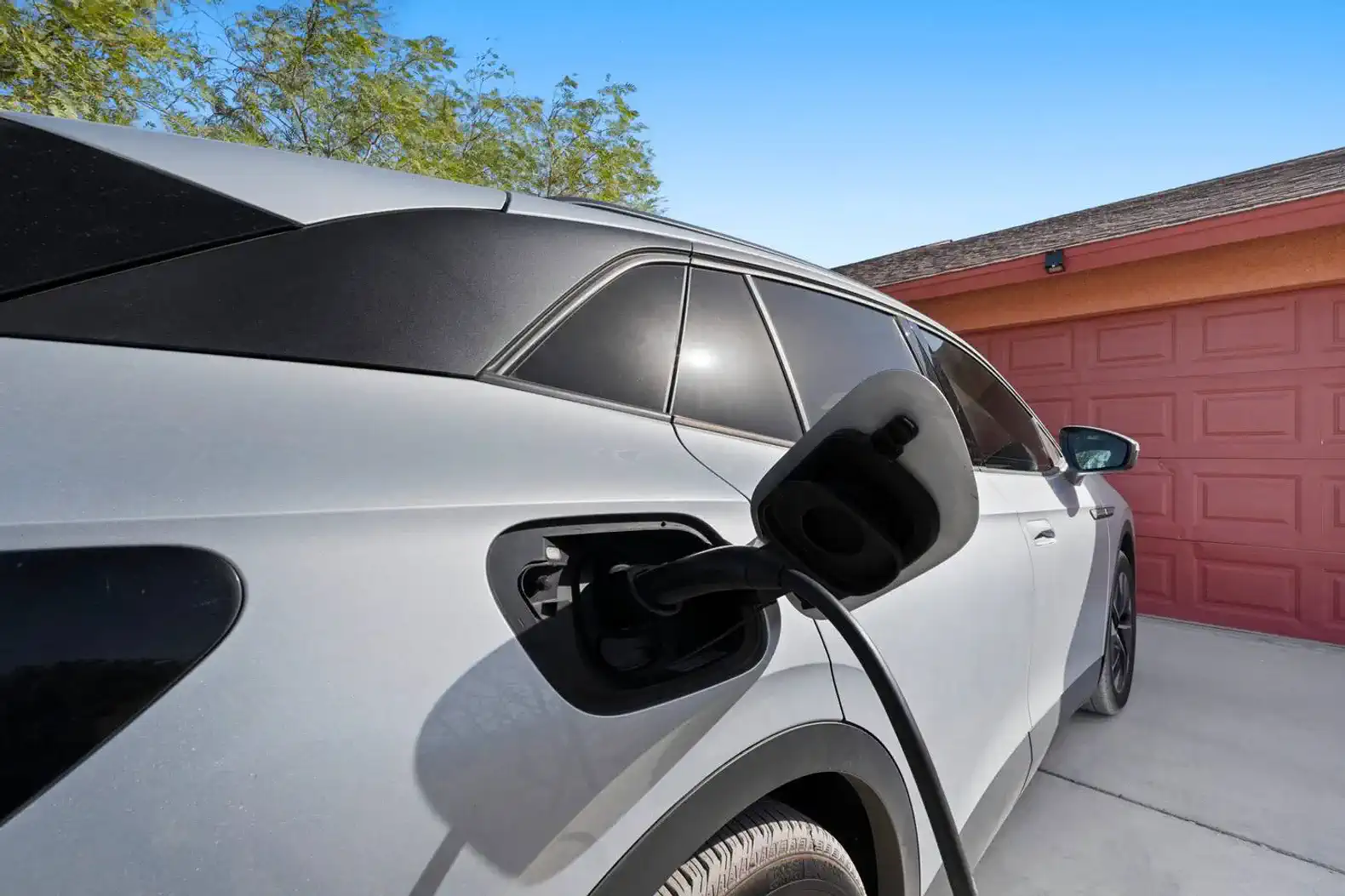 Electric vehicle charging at a home garage with a red door