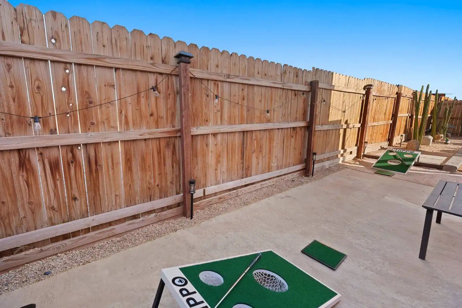 Outdoor area with a fenced yard, string lights, and a putting green