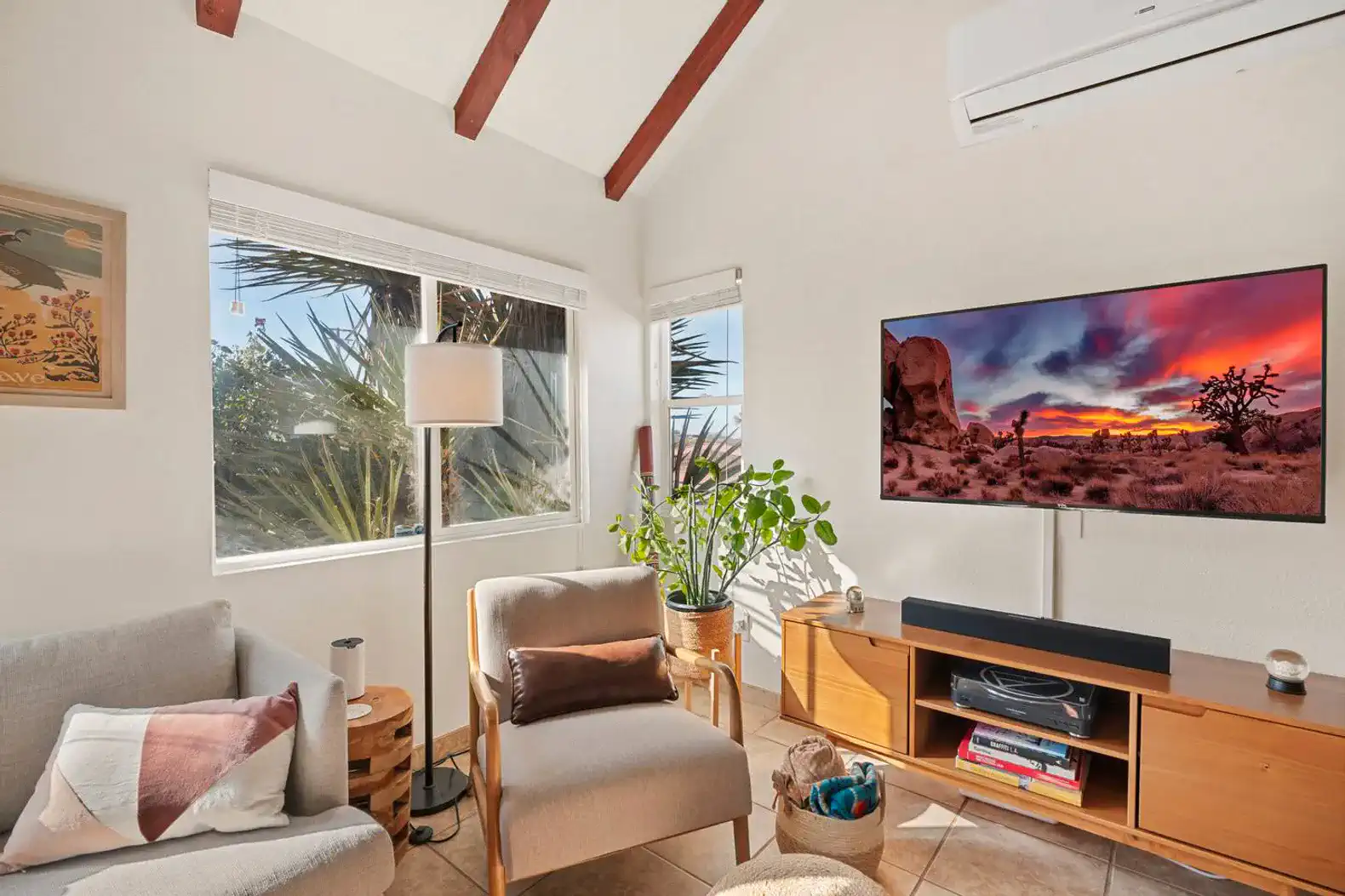 Cozy living room with modern decor, large windows, and a flat-screen TV