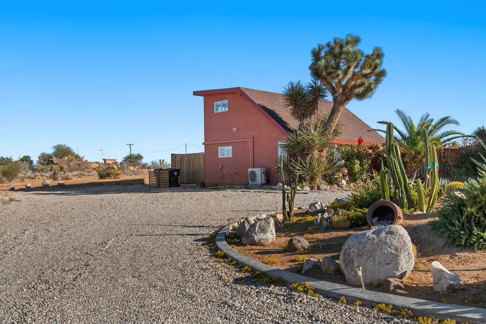 Charming cabin exterior surrounded by desert landscaping and gravel driveway