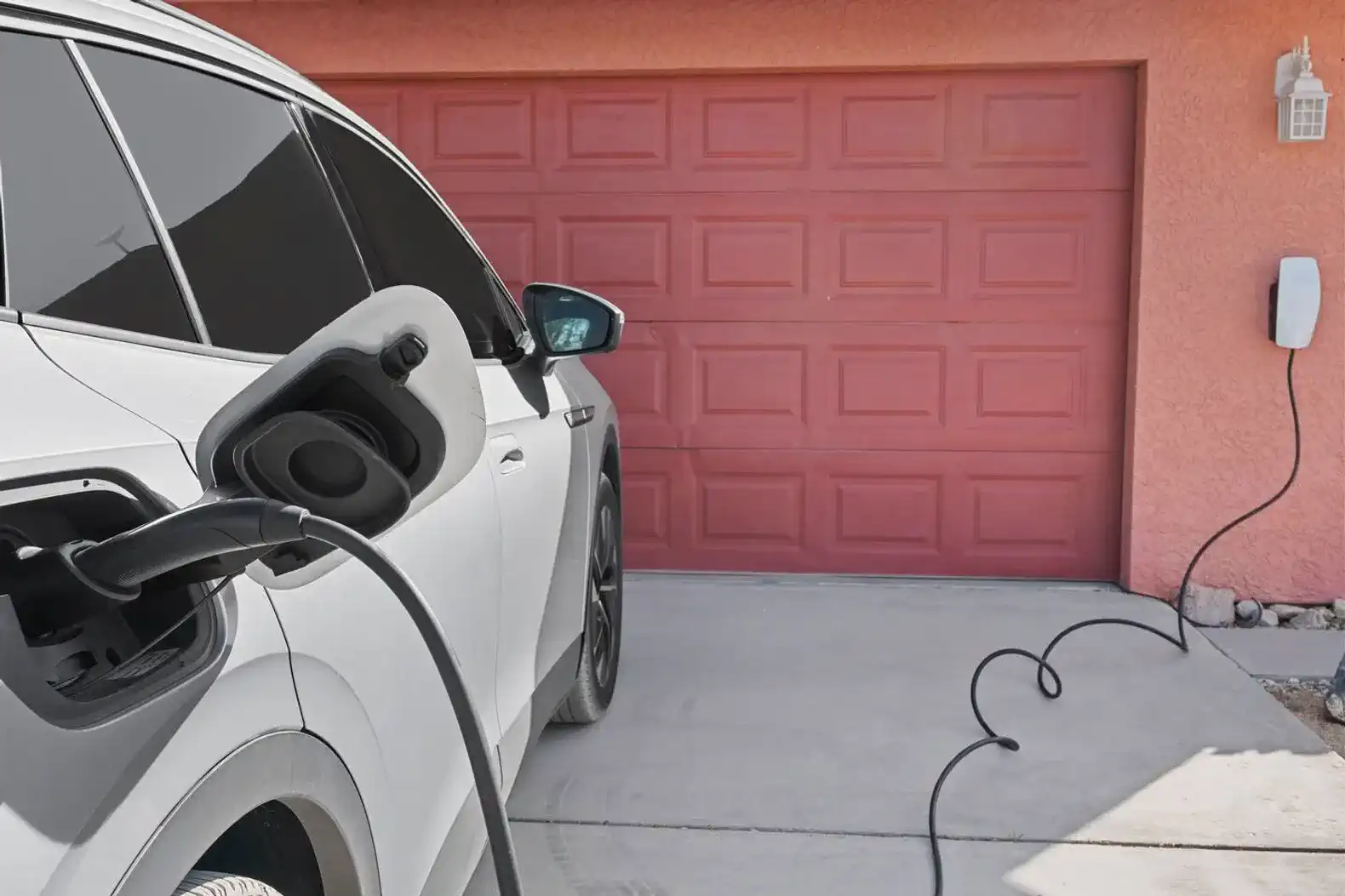Electric vehicle charging in front of a pink garage door