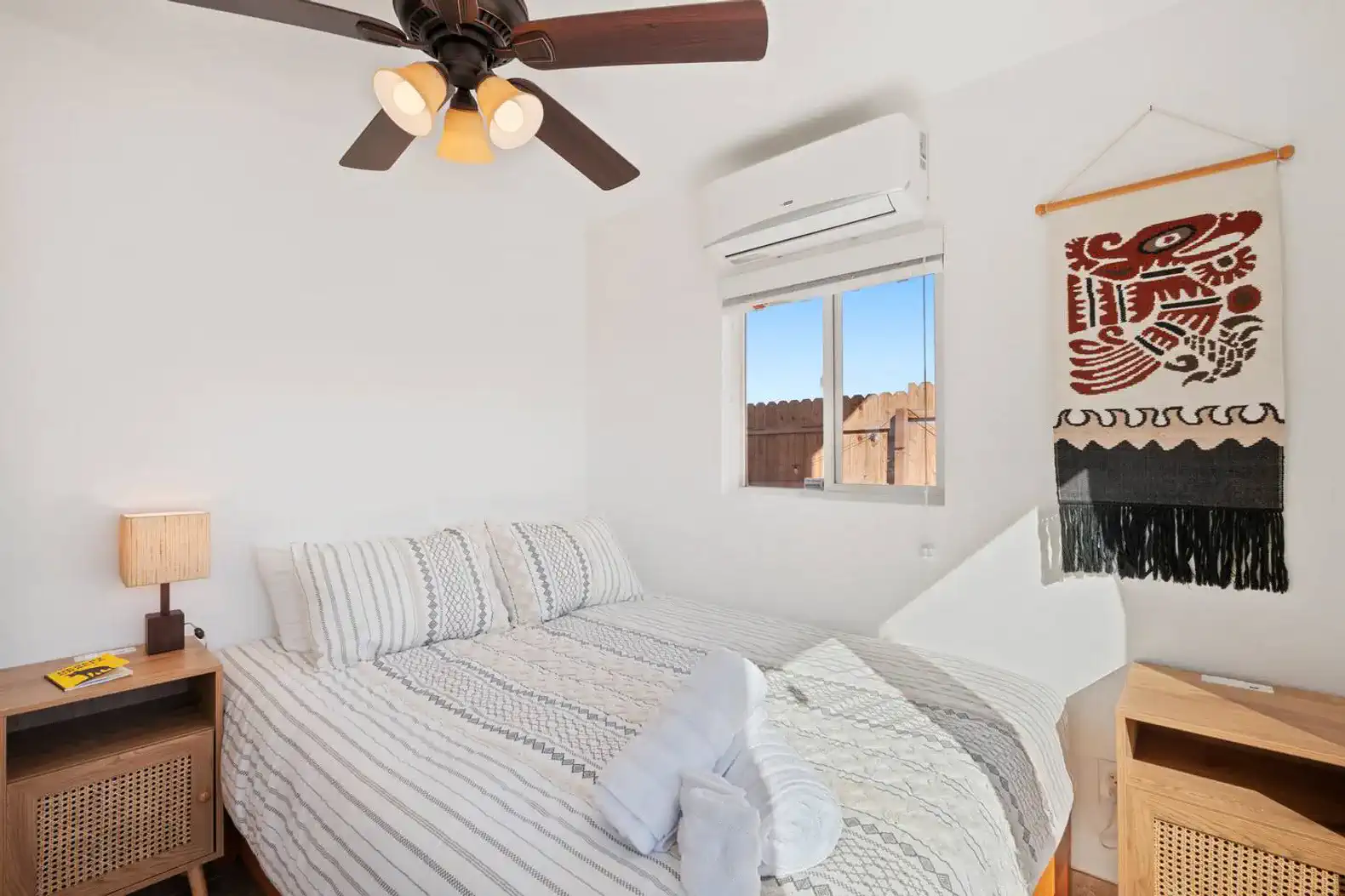 Cozy bedroom with a queen bed, natural light, and decorative wall hanging