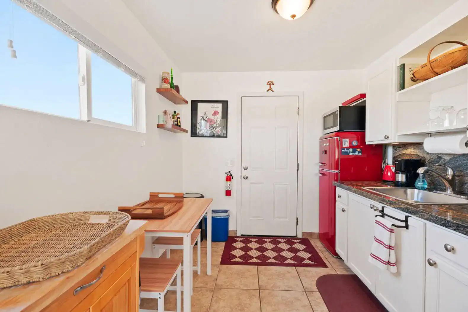 Cozy kitchen with red appliances, wooden table, and ample natural light