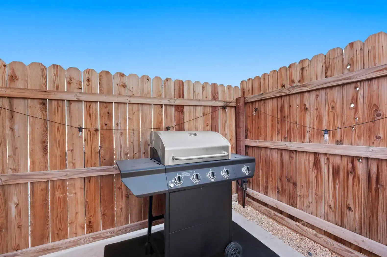 Outdoor grilling area with a barbecue grill surrounded by wooden fencing