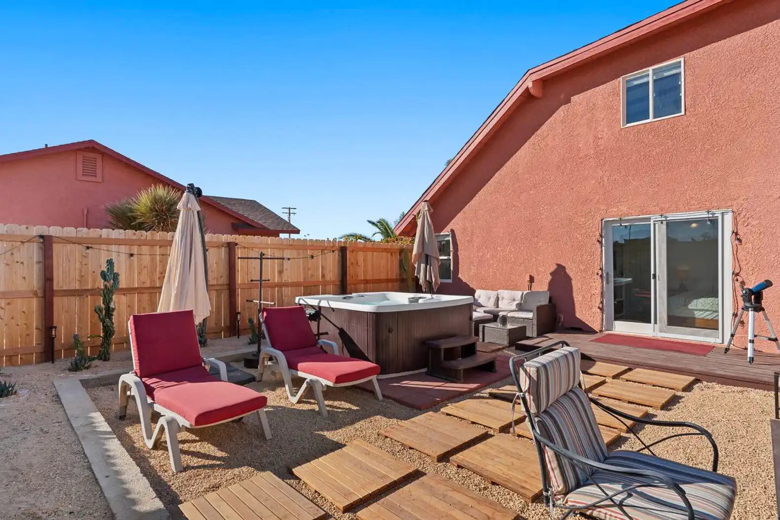 Outdoor area with hot tub and lounge chairs surrounded by a wooden deck