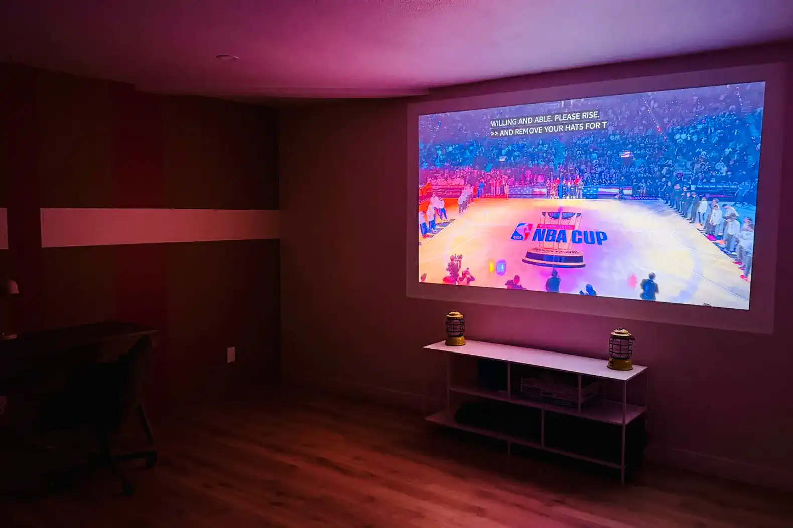 Cozy entertainment area with a large projector screen displaying a basketball game