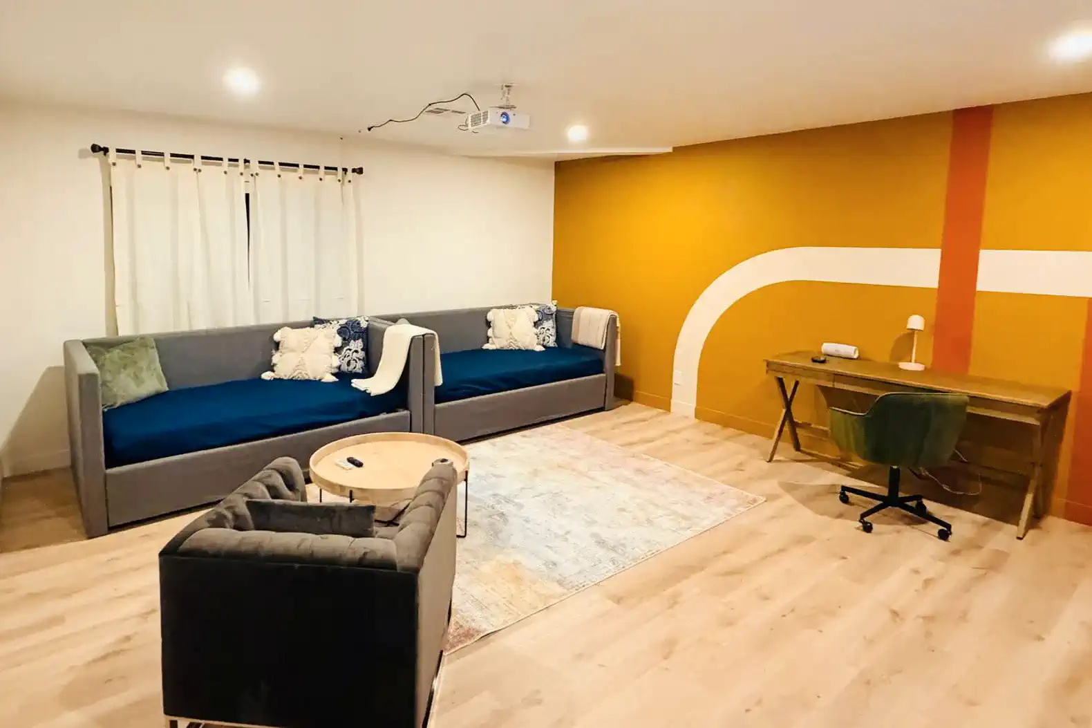 Cozy living area with modern seating and a desk, featuring a colorful accent wall