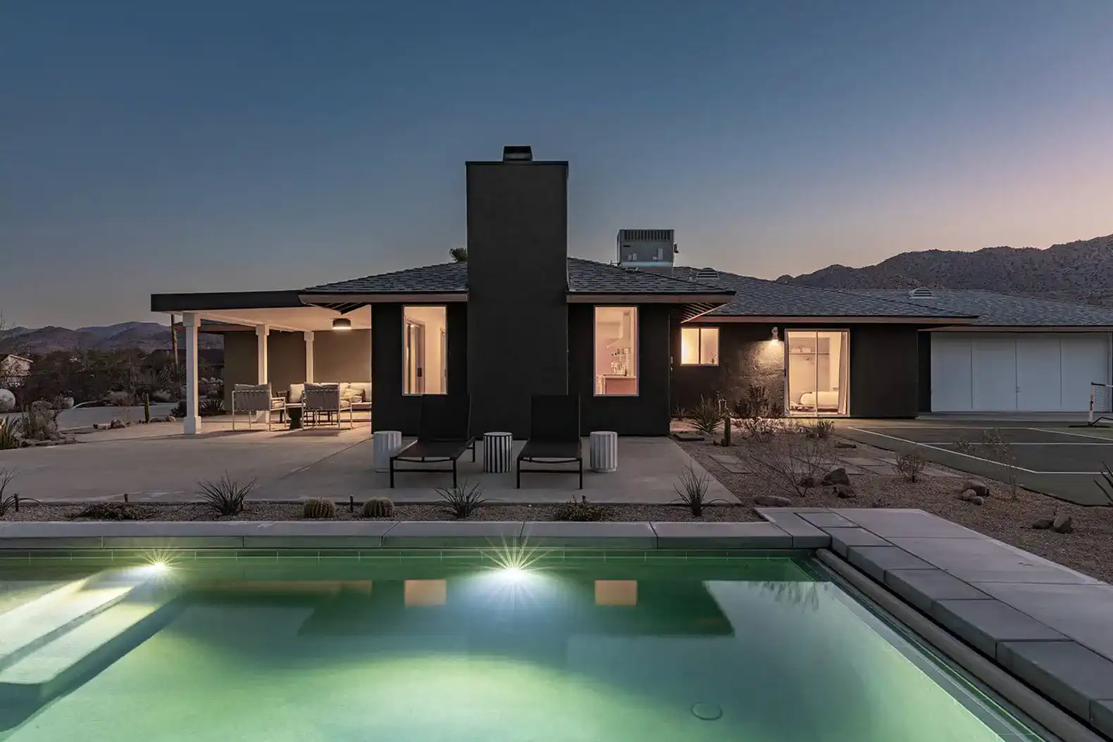 Modern home exterior with pool and patio area at dusk