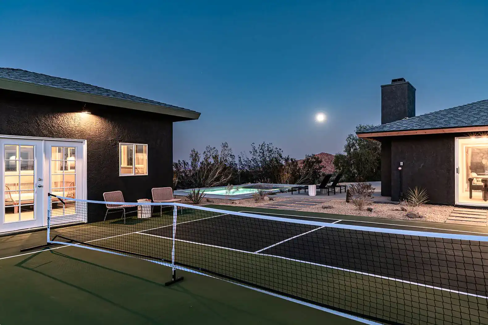 Outdoor pickleball court with moonlit pool and desert landscaping