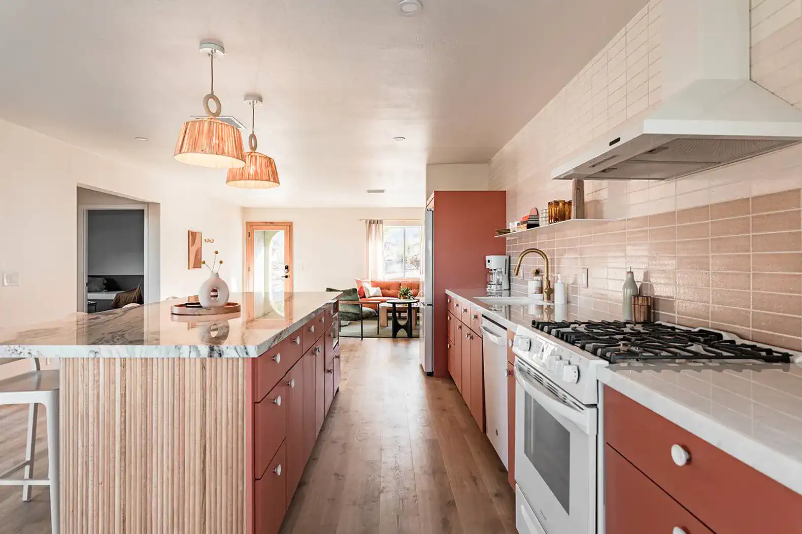 Modern kitchen with pink cabinets, marble countertops, and pendant lighting