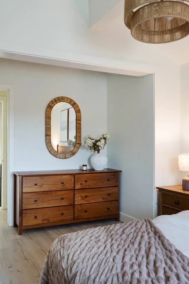 Chambre confortable avec une commode en bois, un miroir décoratif et une literie douce