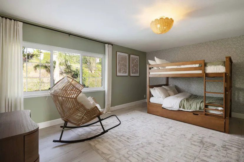 Chambre avec lits superposés confortable avec un fauteuil à bascule et de la lumière naturelle provenant d'une grande fenêtre