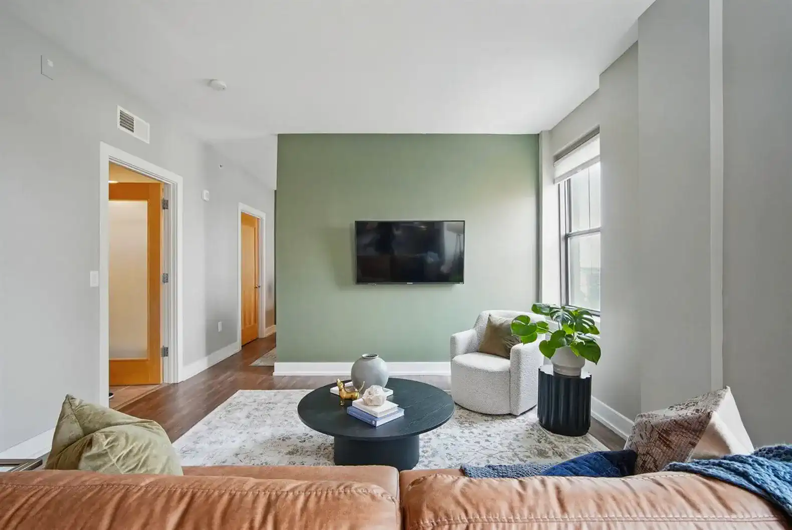 A stylish lounge chair with a soft throw pillow and potted greenery create a calm corner for morning coffee or evening reads.