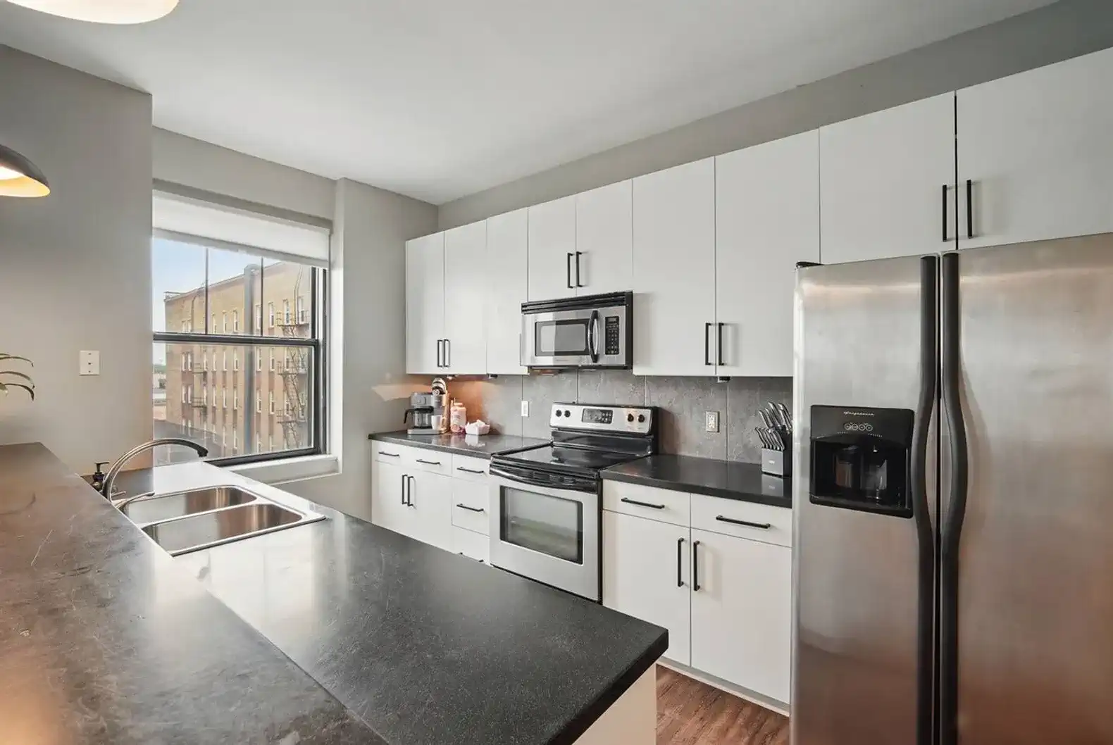 Fully equipped kitchen with stainless steel appliances, ample cabinet space, and a large window overlooking downtown Des Moines.