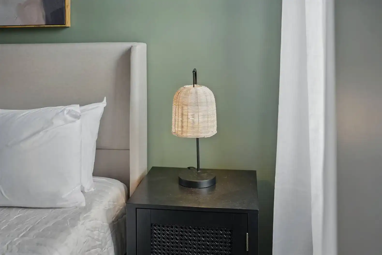 Stylish black nightstand with a warm rattan lamp adds a cozy glow to your evenings. A functional and modern touch right next to your bed.