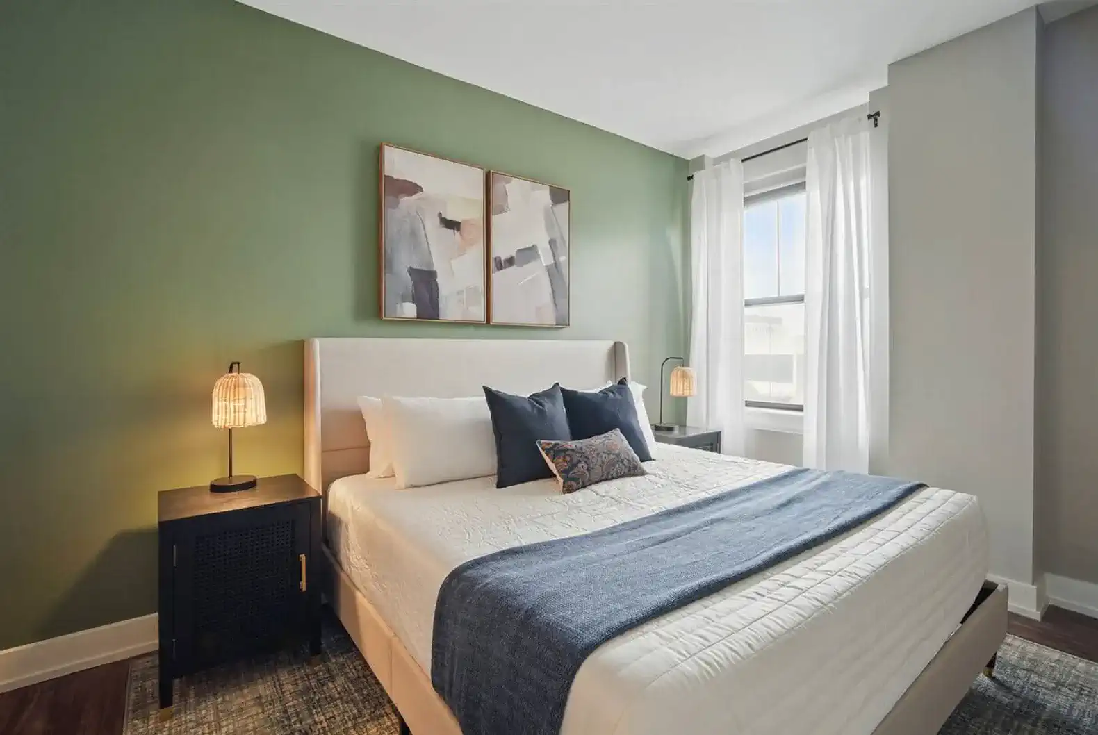 Spacious bedroom with a plush king bed, layered linens, and a calming green accent wall. Designed for restful nights and stylish mornings.