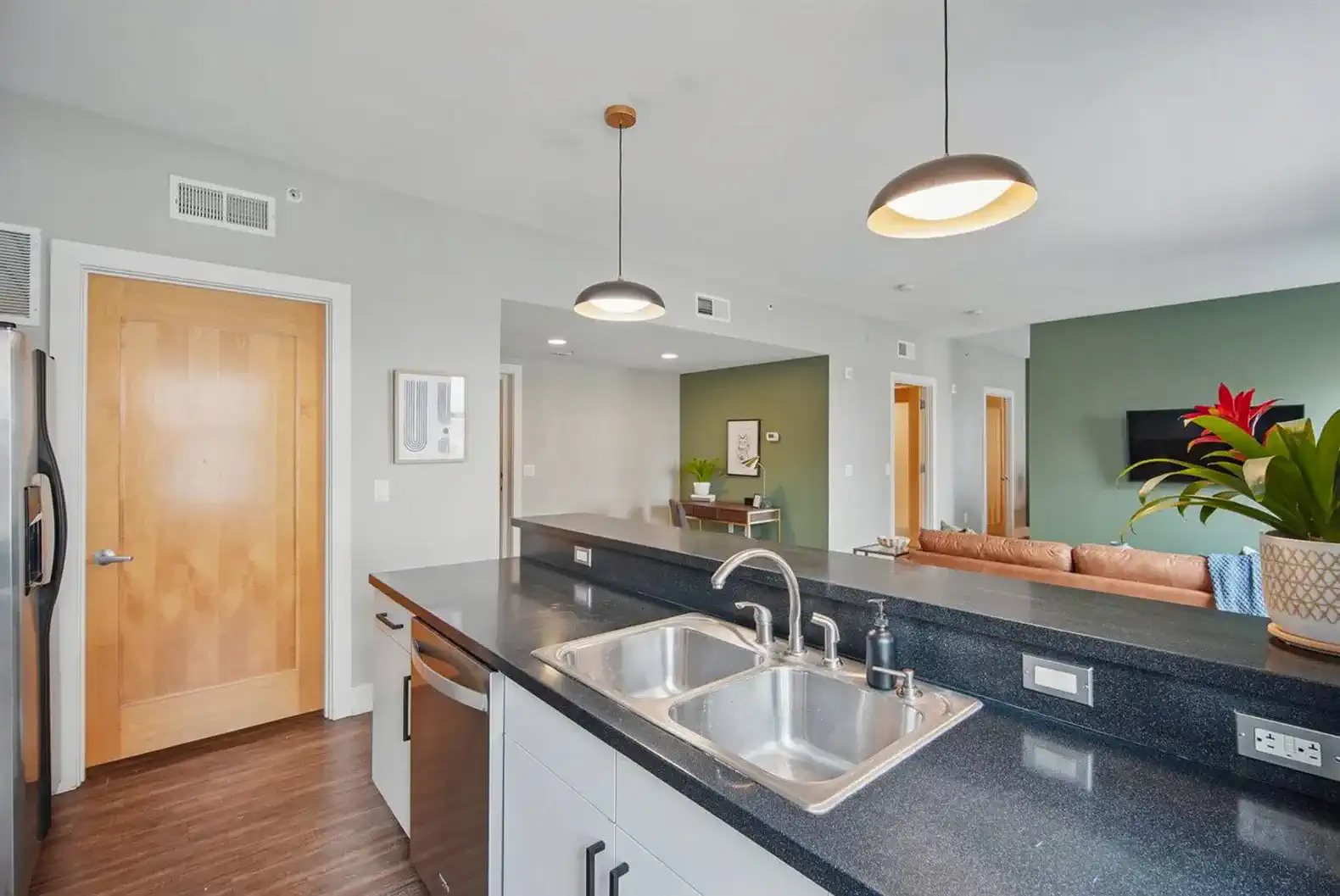 Sleek and functional kitchen island featuring a double sink, modern fixtures, and a view into the open-concept living space.