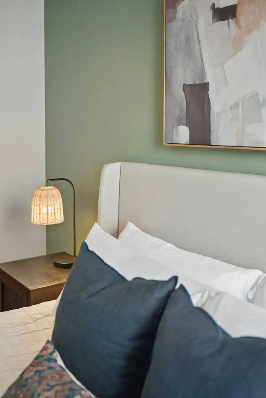 Soft neutral bedding, bold accent pillows, and abstract wall art create a calming and modern bedroom environment perfect for restful nights.