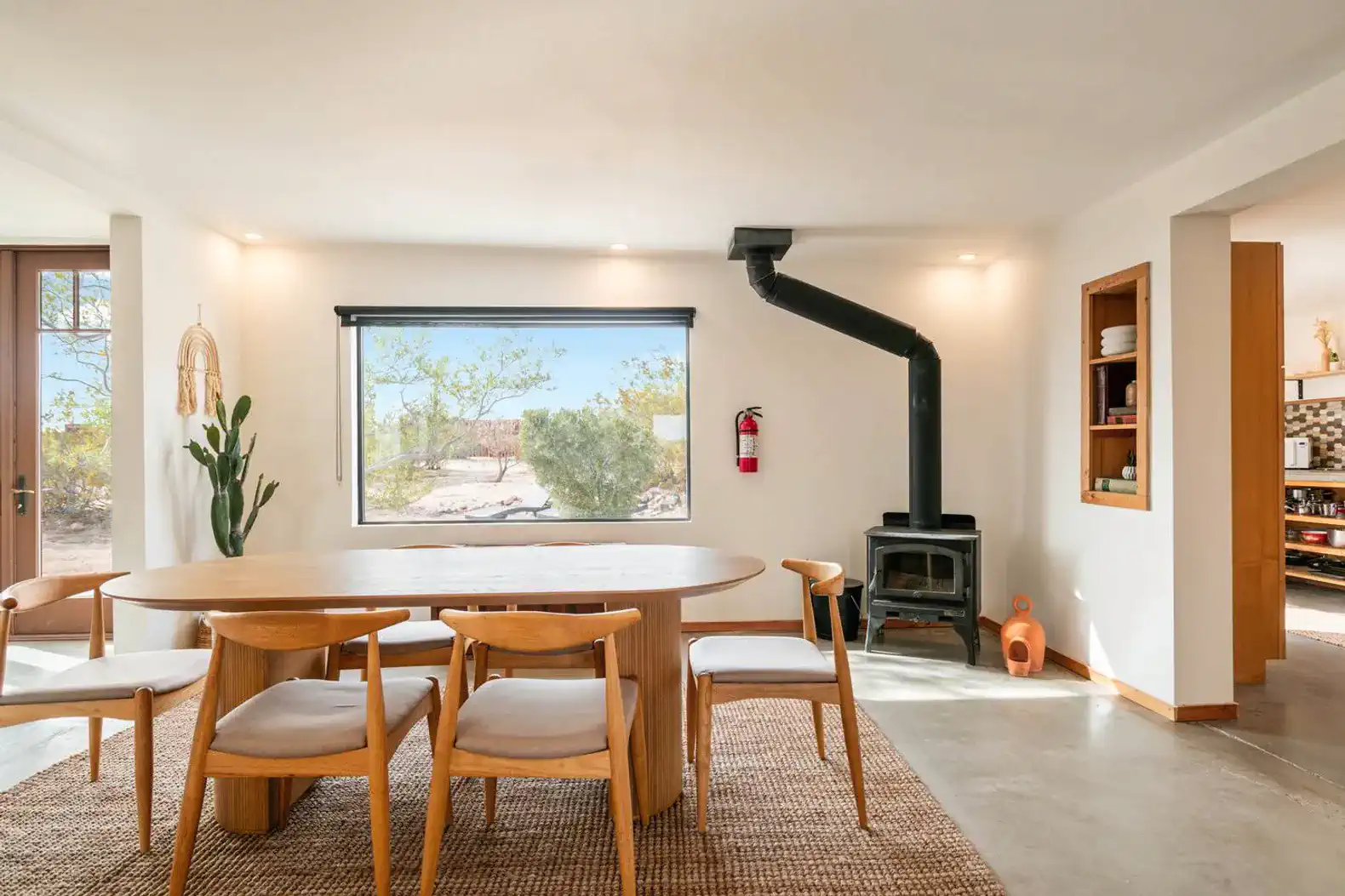 Spacious dining area with a wooden table and modern chairs, featuring a cozy wood stove