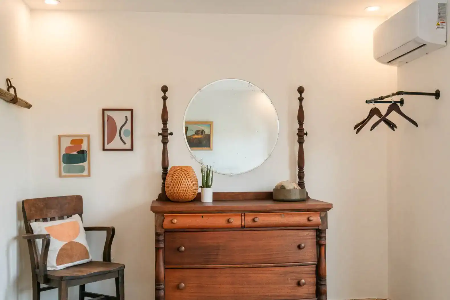 Cozy entrance area with a wooden dresser, mirror, and decorative artwork